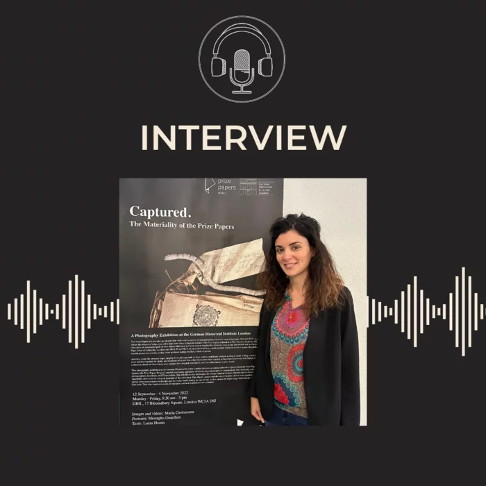 Maria Cardamone in front of a poster relating to the Prize Papers project at the National Archives, on a black background, with the GHIL podcast symbol of a microphone and headphones in a circle.