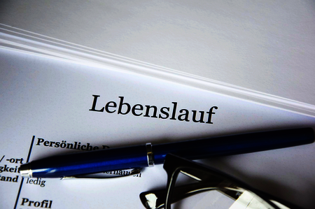 A pen and a pair of glasses on top of a CV entitled Lebenslauf
