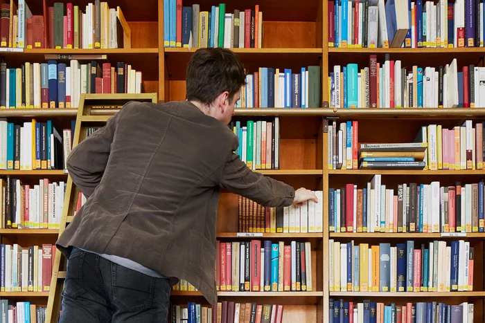 A reader climbing one of the library ladders to reach a book on the higher shelves.