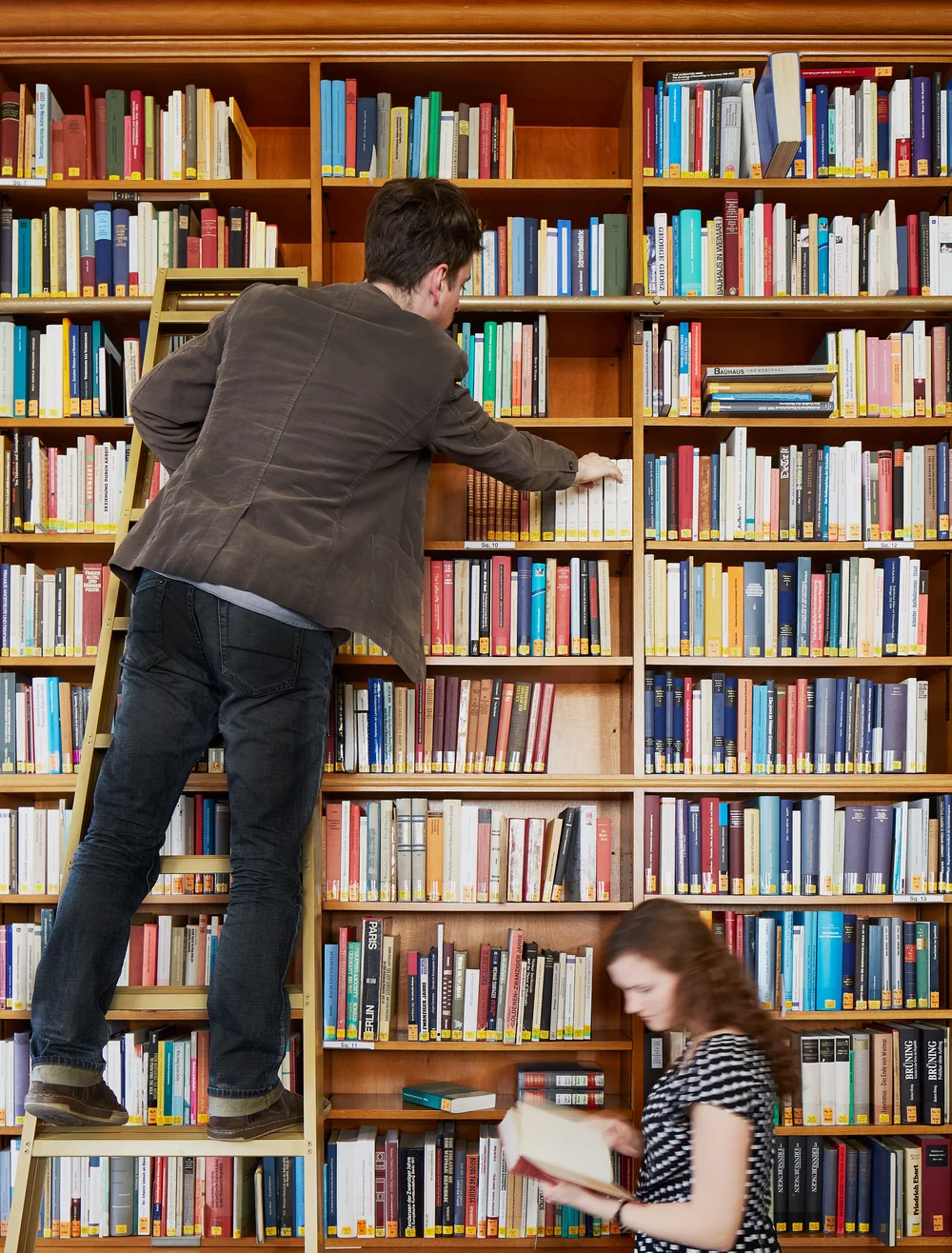 A reader climbing one of the library ladders to reach a book on the higher shelves.