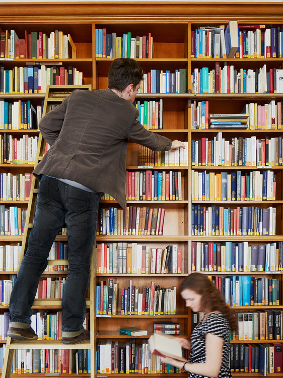 A reader climbing one of the library ladders to reach a book on the higher shelves
