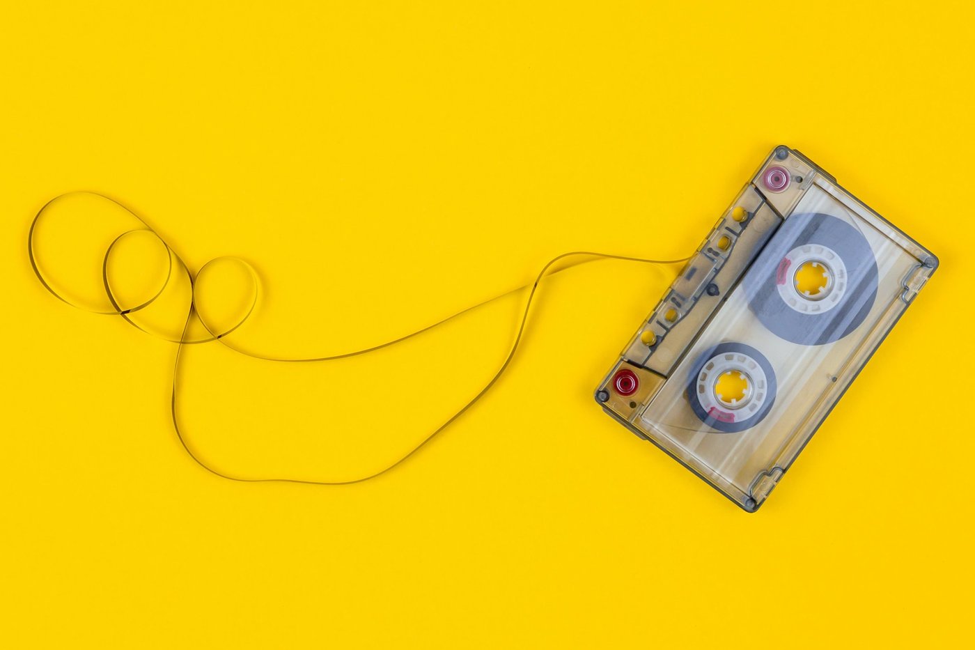 Top view of audio cassette with tangled tape on bright yellow background 