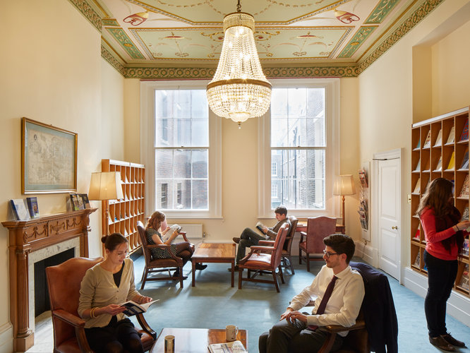 Several people seated or browsing the periodcals shelves in the Common Room